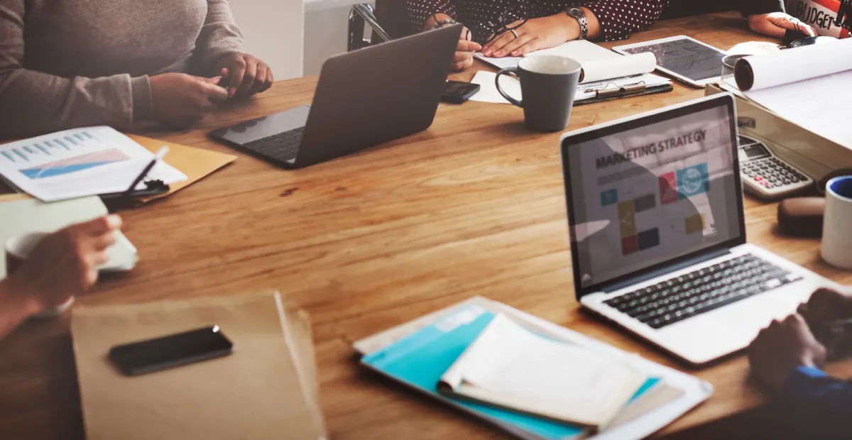 Equipo de una agencia trabajando en una mesa con portátiles